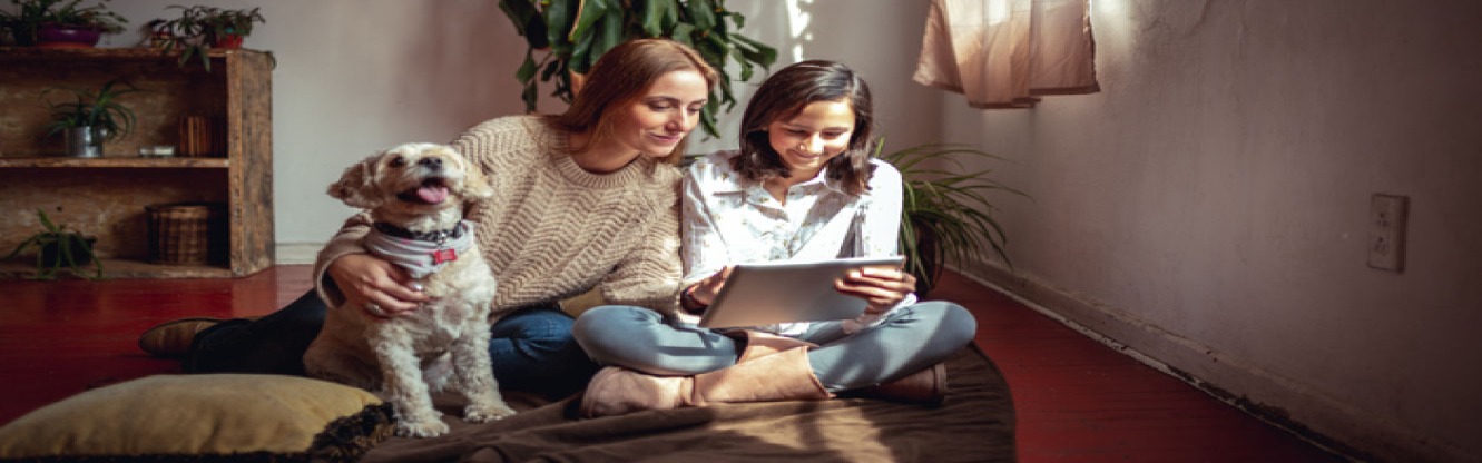 Mother and daughter sitting on couch with dog.
